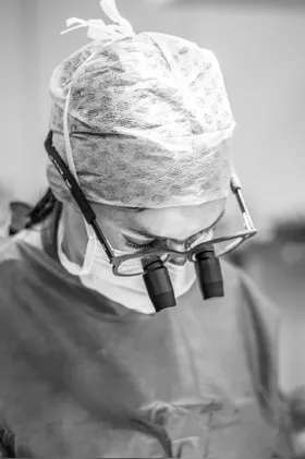 Le Dr Charlotte Waxweiler en tenue chirurgicale, loupes de précision sur les yeux