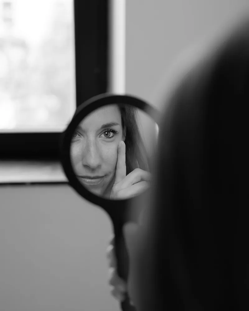 Le Dr Charlotte Waxweiler observant son visage dans un miroir à main